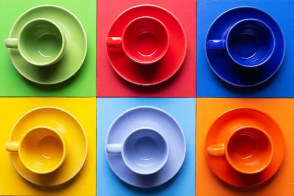 Varias tazas de café de diferentes colores, mostrando cómo el color afecta la percepción del sabor según la teoría del color marketing.